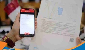 Seseorang memegang smartphone menampilkan aplikasi Sentuh Tanahku.