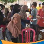 Suradi (kiri) saat menyerahkan kantung daging kurban kepada salah satu perwakilan warga pemegang kupon resmi.