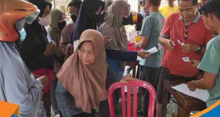 Suradi (kiri) saat menyerahkan kantung daging kurban kepada salah satu perwakilan warga pemegang kupon resmi.